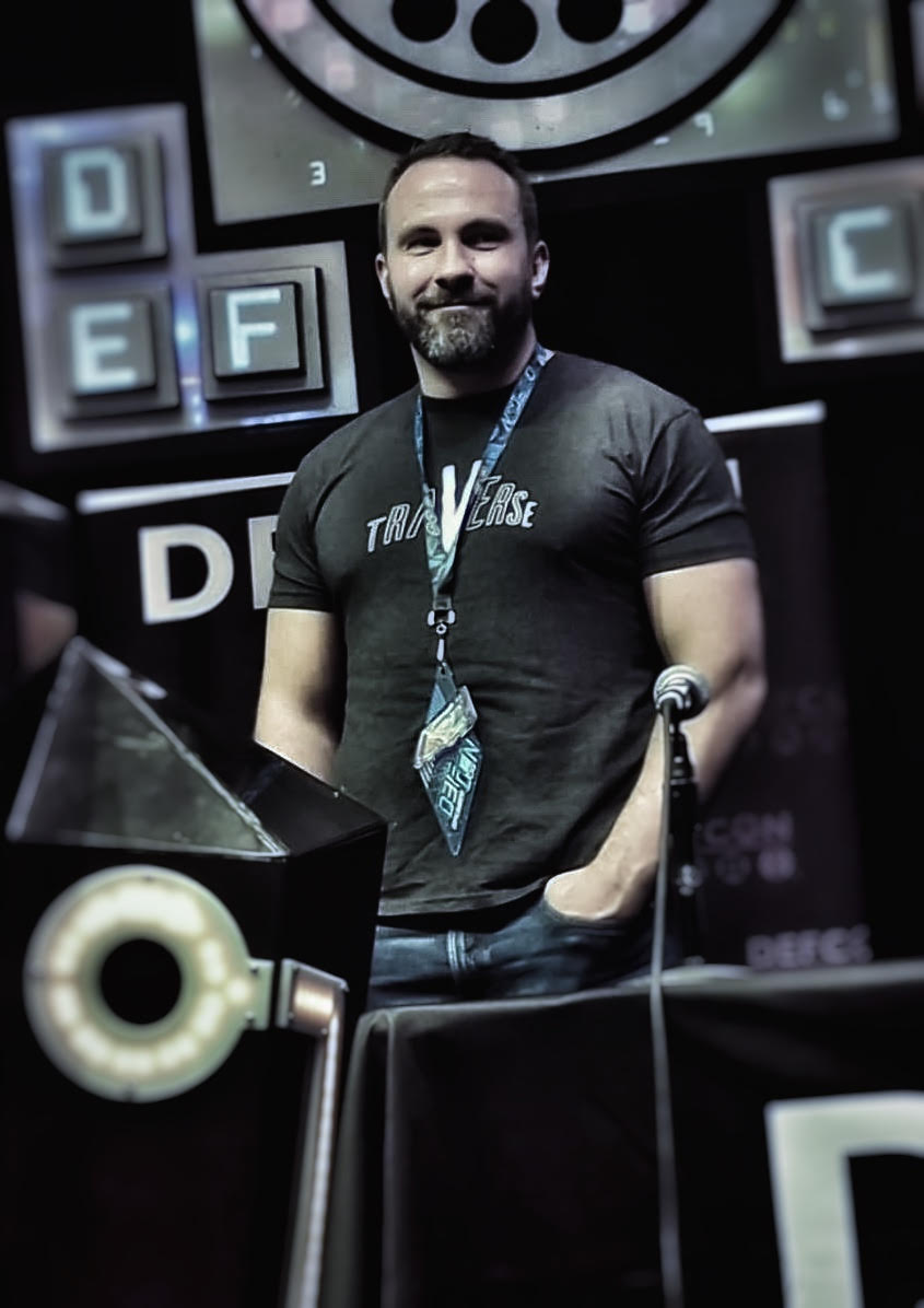 Austin Shamlin, founder of the Traverse Project, a Texas-based group that investigates perpetrators of sex trafficking and child exploitation, stands at a microphone wearing a Traverse Project T-shirt.