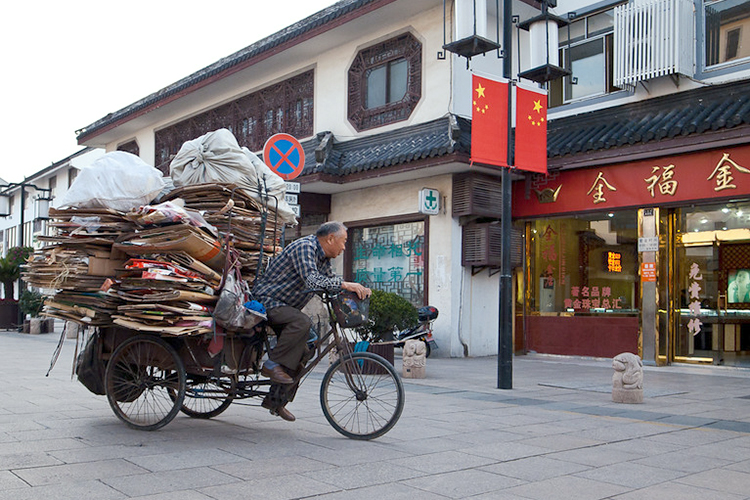 man riding bike in China carrying cardboard