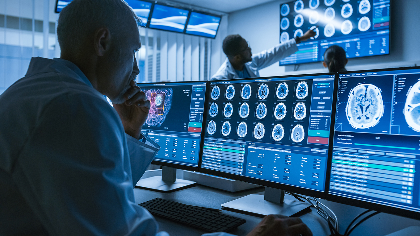 Researcher looking at brain scan images on computer monitors.