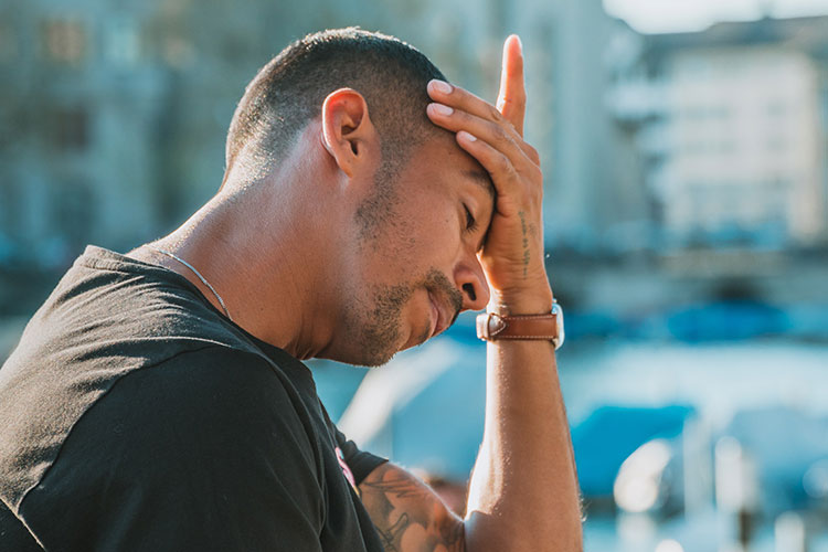 despairing man rests with hand to his forehead