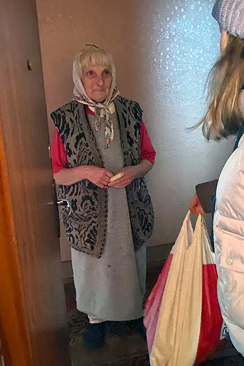 a volunteer from Support Ukraine With Us delivers donated food to an older woman who has not been able to flee the bombardment of Kharkiv