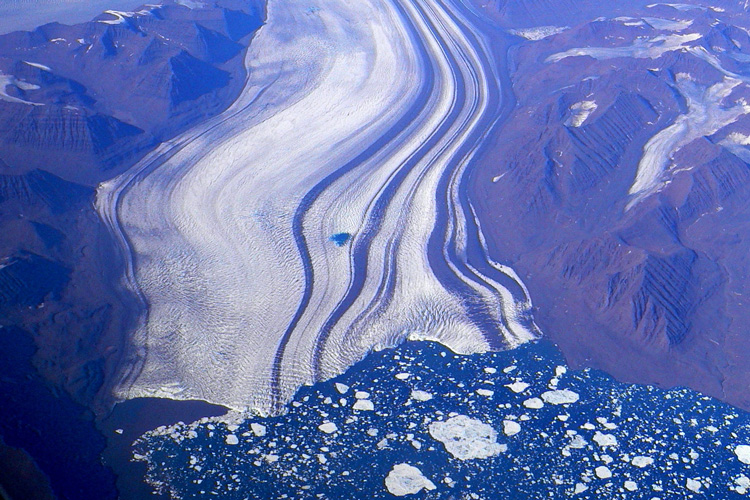 aerial view of striped glacier terminating in the ocean