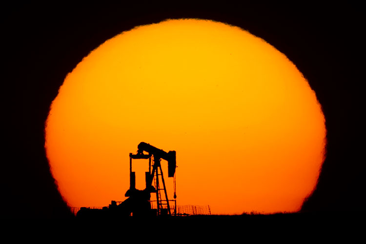 an idle oil derrick silhouetted against a flaming orange sun