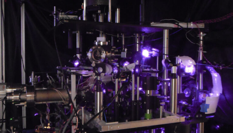 purple laser light illuminates optical bench in dark room