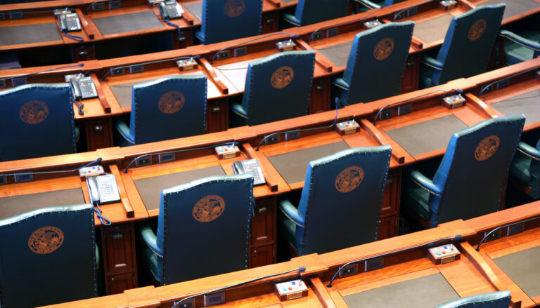 arcing rows of empty chairs in a legislative chamber