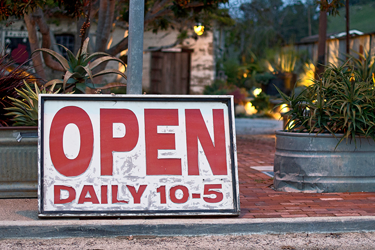 open sign leaning against a pole outside