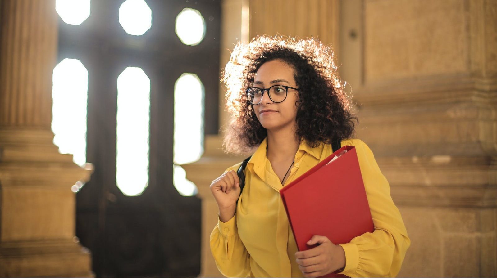 Woman holding red binder inside of a building.