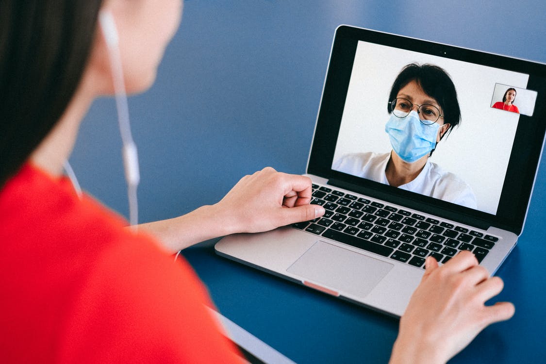 Person on a video call with another person wearing a mask, presumably a doctor