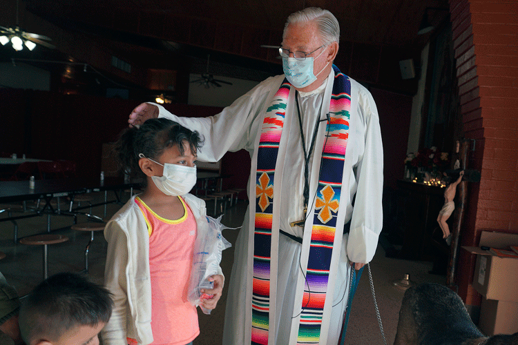 a priest wearing a surplice and a colorful stole around his neck meetings with young immigrant children