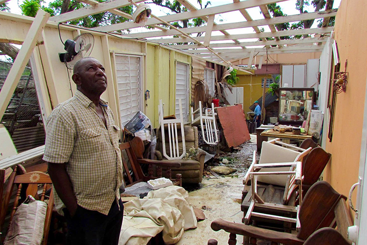 a person looks at his house in Puerto Rico that was destroyed by a hurricane