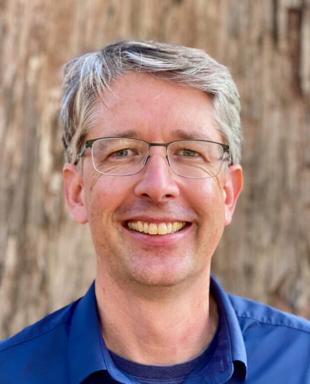 image of headshot of man in glasses smiling 