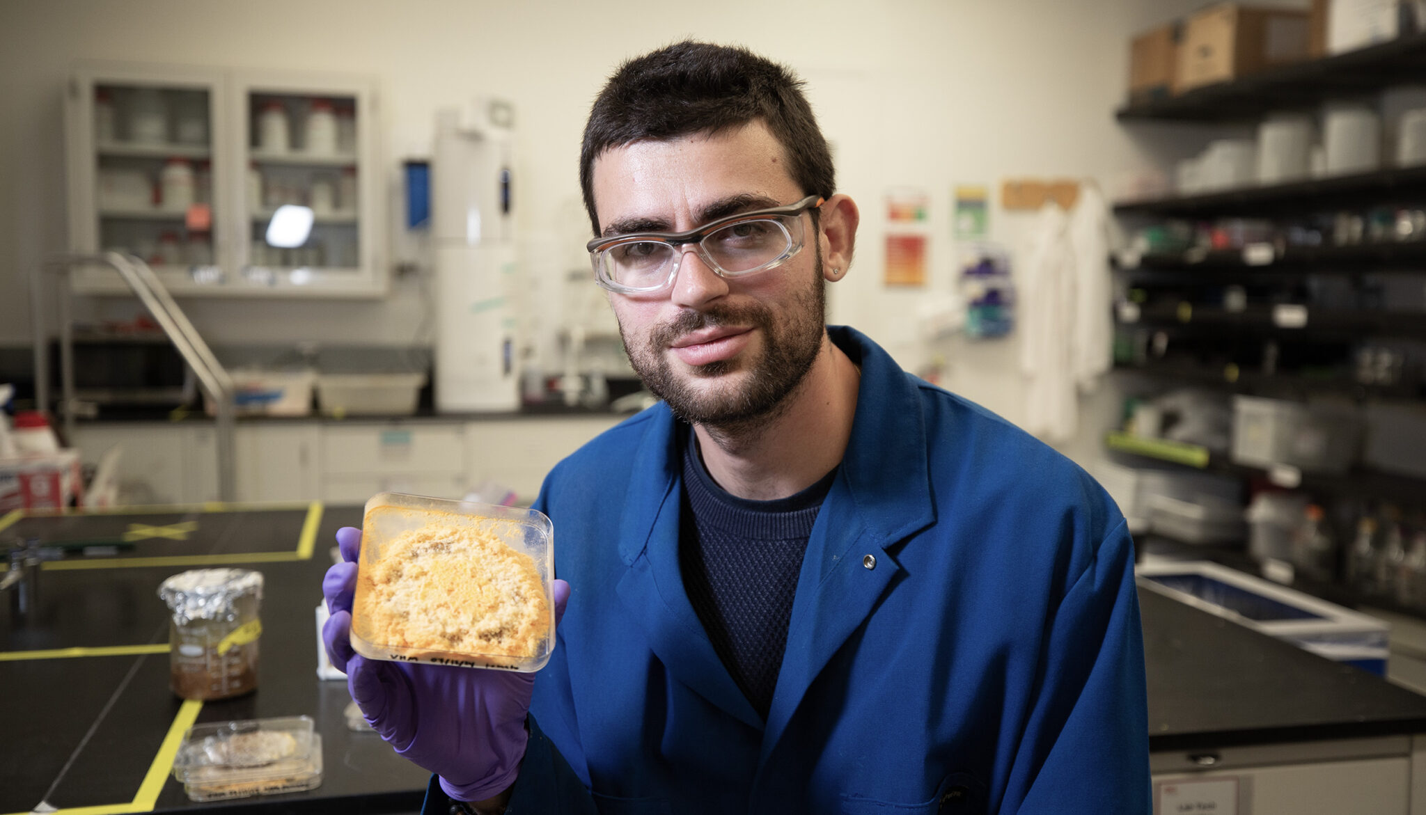 image of man holding a petri dish with mold in it