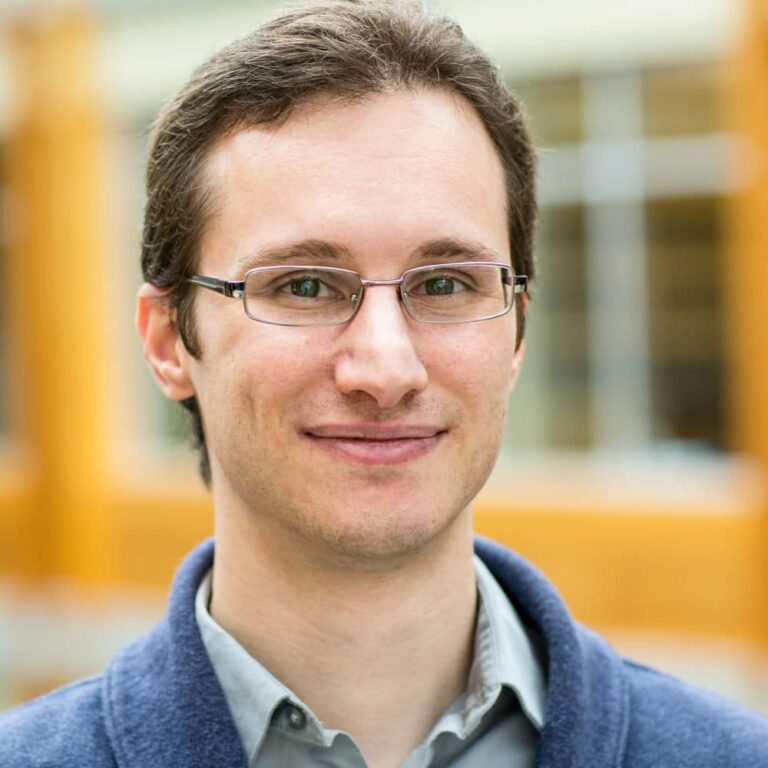 headshot of man smiling with glasses 