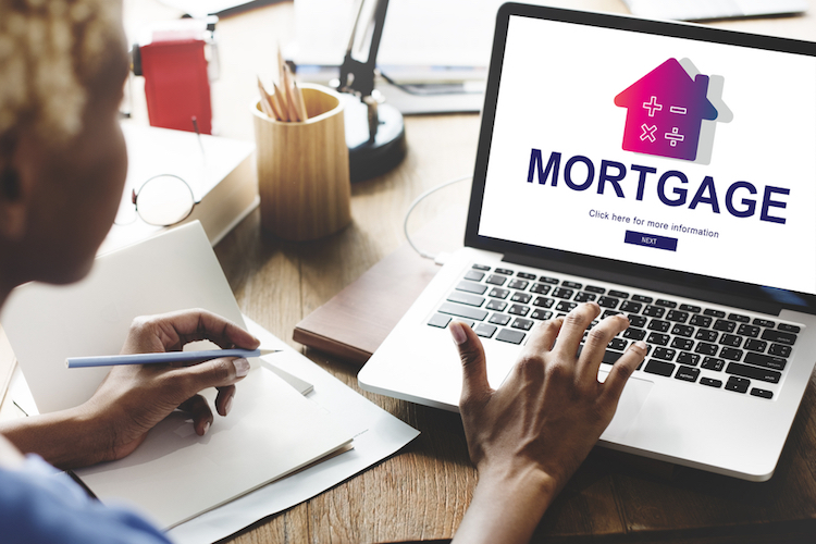 a woman sits at a computer with the word mortgage on the screen