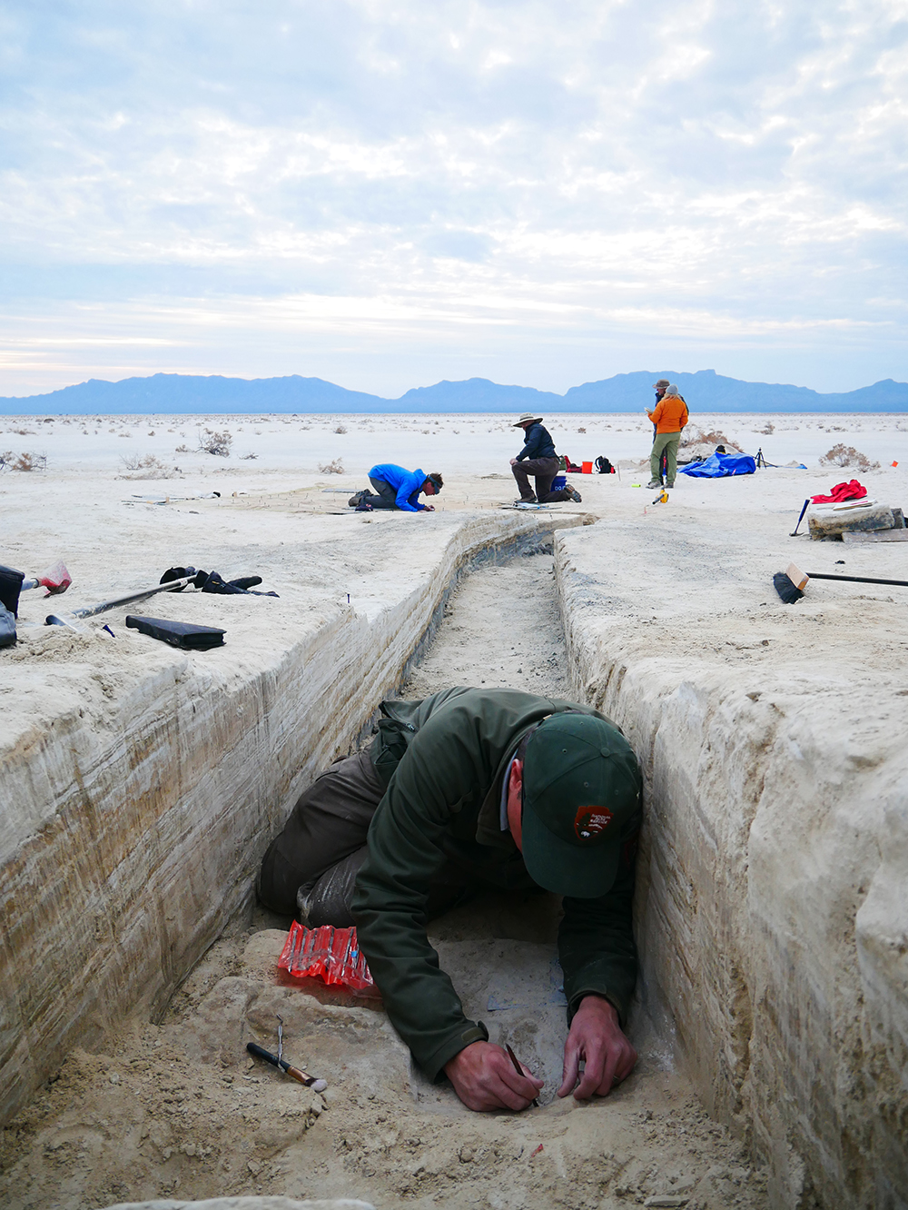 man in trench with white sands in background