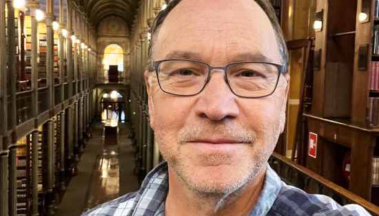 headshot of man in glasses smiling