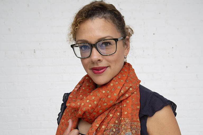 Tina Sacks, professor of social welfare looks at the camera with an orange scarf