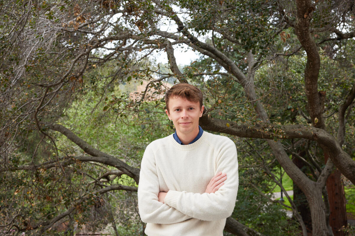 headshot of man standing in front of trees