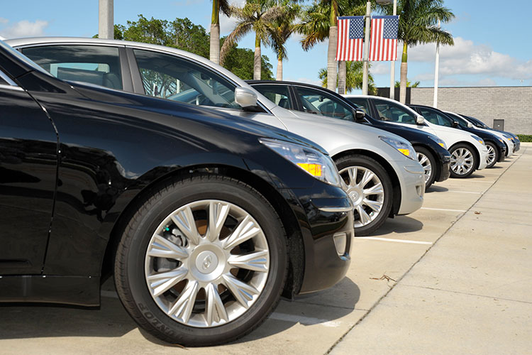 a line of cars for sale with US flags in the background