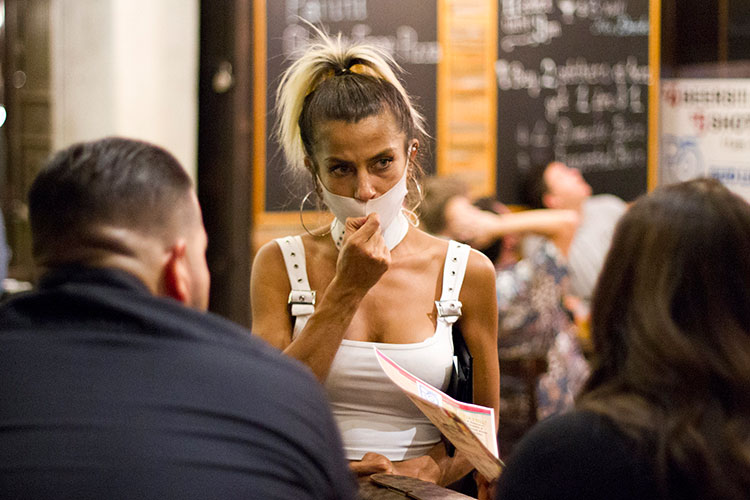 female restaurant server, wearing a mask to protect from coronavirus, takes an order