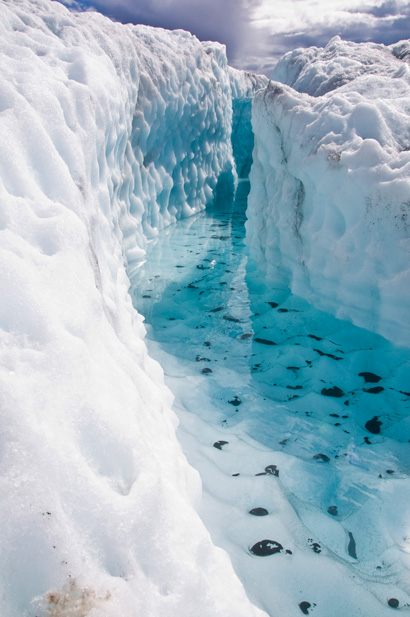 clear, blue water-filled crevasse in glacier
