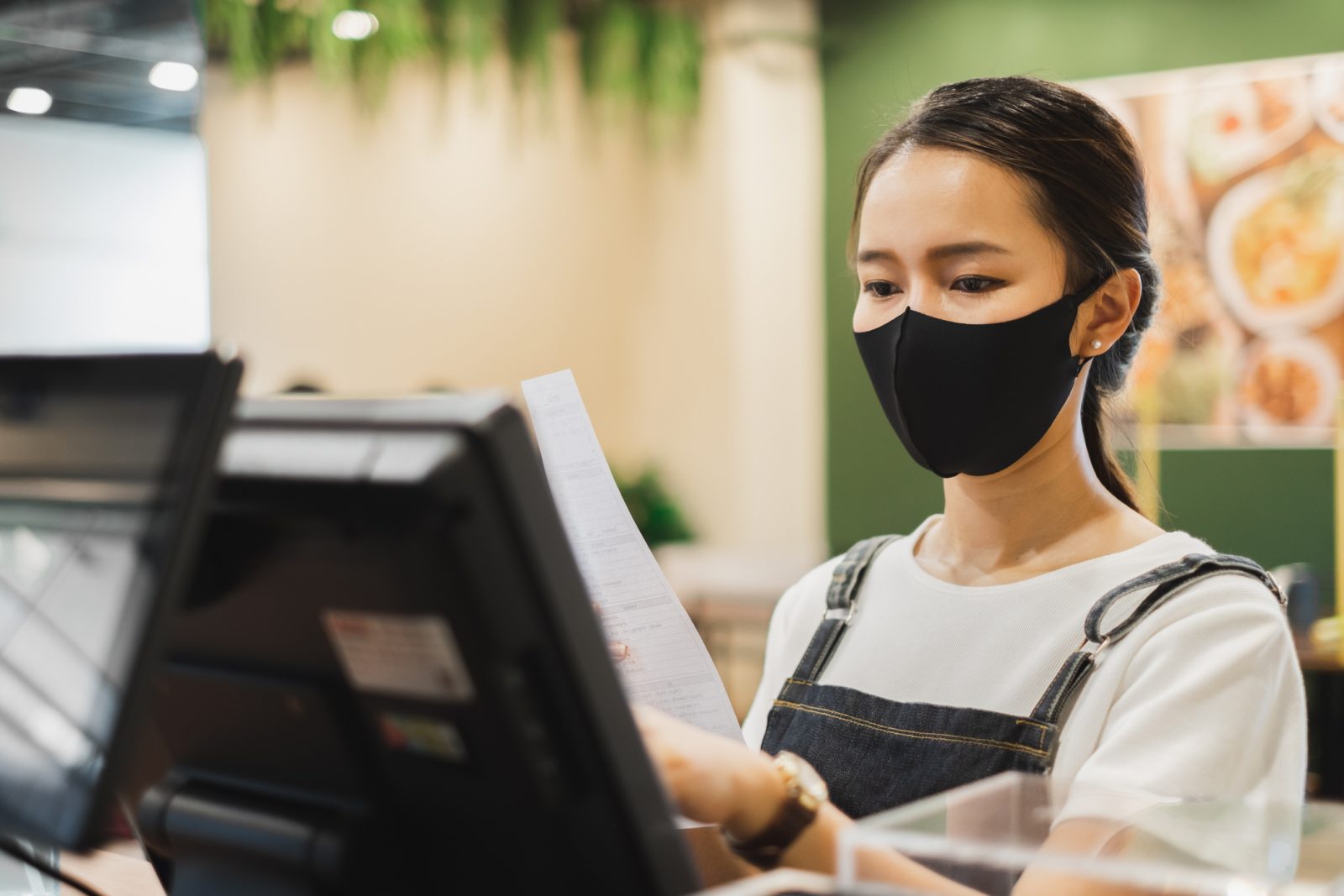 Asian staff restaurant waitress wear protective face mask working in the restaurant with social distancing to protect infection from coronavirus covid-19