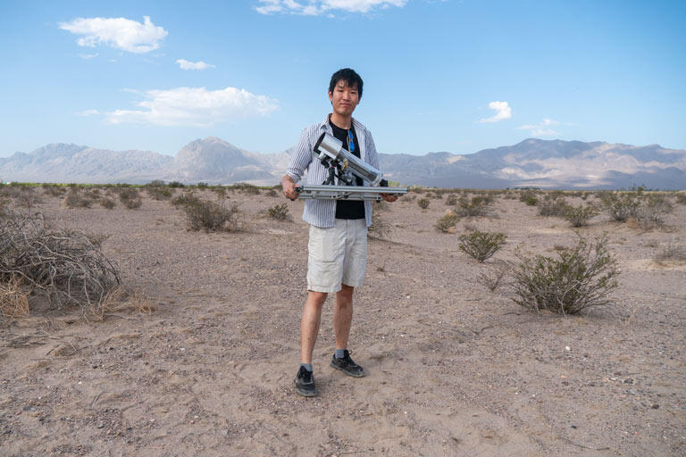 Zhiling Zheng holding a MOF-powered water harvester in the desert