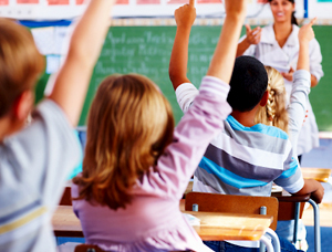 Stock photo of students raising their hands in class.