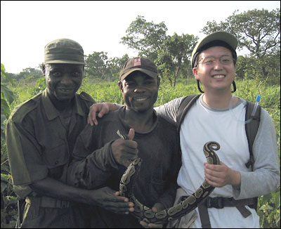 Three men hold a python.