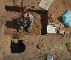 Hastorf sits in a small pit excavating the area.
