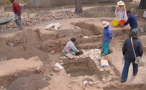 Six archeologists excavate an area of land.