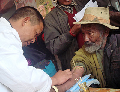 A researcher collecting blood from an old Tibetan man.
