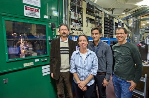 Four researchers stand outside a large lab door.