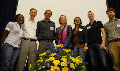 Seven researchers stand with flowers.