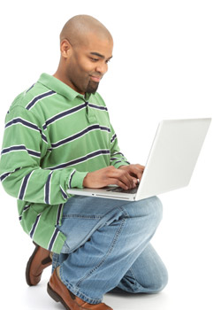 A stock photo of a black man typing on a laptop.