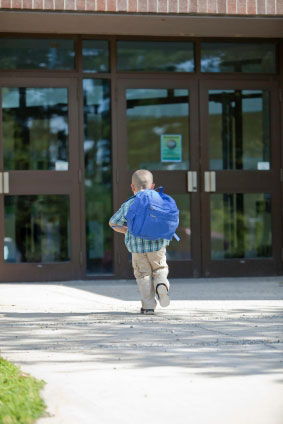 Stock photo of a kid running into school.