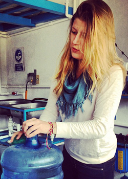 Rebecca Peters in lab with hands on the neck of a large water bottle