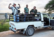 Three researchers stand in the back of a truck.