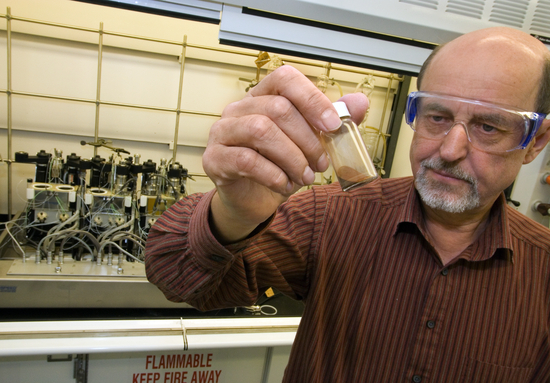 A man holds up a small testube of powder.