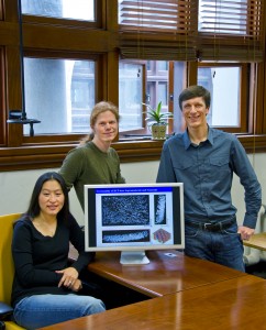 Three researchers stand by a computer system.