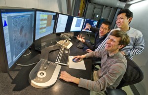 Three researchers look at a computer model.
