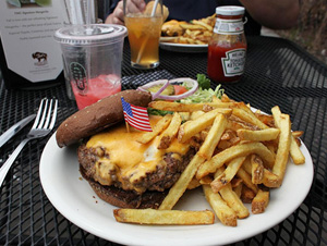 A plate of burger and fries with a small American flag in the center.