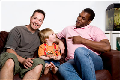 Two fathers sit with their young son.