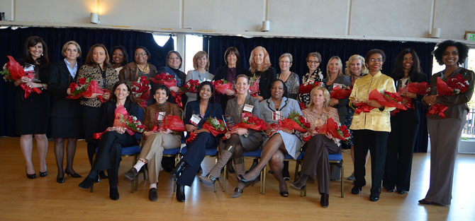 A group of women hold bouquets of red flowers.