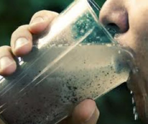 person drinking from glass of dirty water