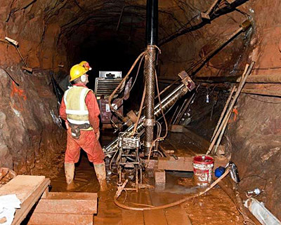 A researcher stands next to a drill in a cavern.