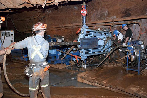 researchers underground drilling into the walls of a mine.