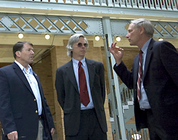 Three men in suits speak.