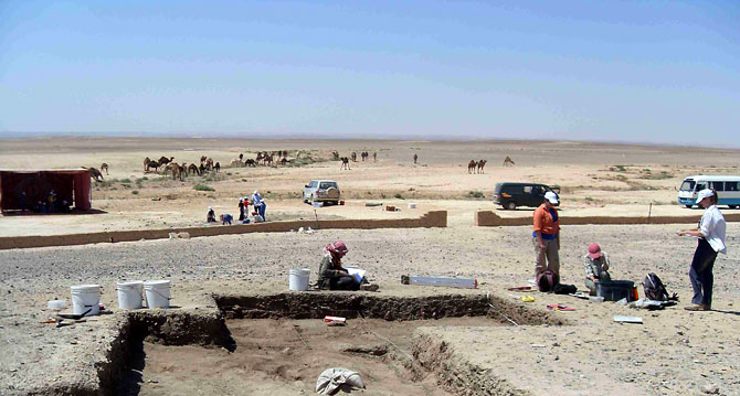Archeologists excavate in a vast desert area.