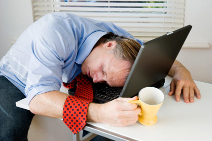 Stock photo of a man falling asleep at his desk computer.